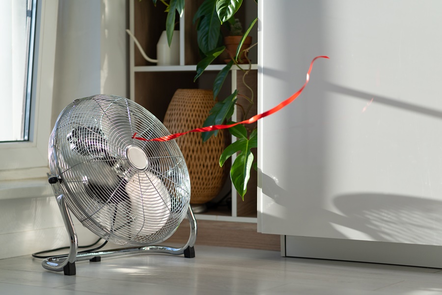 Ventilador de suelo con carcasa metálica impulsando aire en una habitación, representando el flujo de aire típico en la comparativa climatizador vs ventilador.