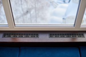 Rejillas de ventilación integradas bajo la ventana, parte de un sistema de ventilación mecánica controlada para regular la temperatura del hogar.