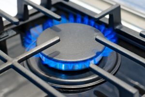 Fogón de cocina a gas encendido con llama azul, ilustrando la importancia de cumplir la normativa rejillas de ventilación para gas natural.